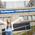 MacKid Kate standing in front of McMaster Children's Hospital