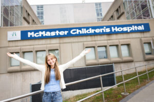 MacKid Kate standing in front of McMaster Children's Hospital